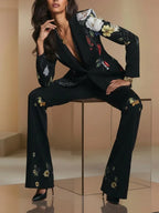 Traje de dos piezas compuesto por blazer y pantalón de un solo botón con estampado floral negro.